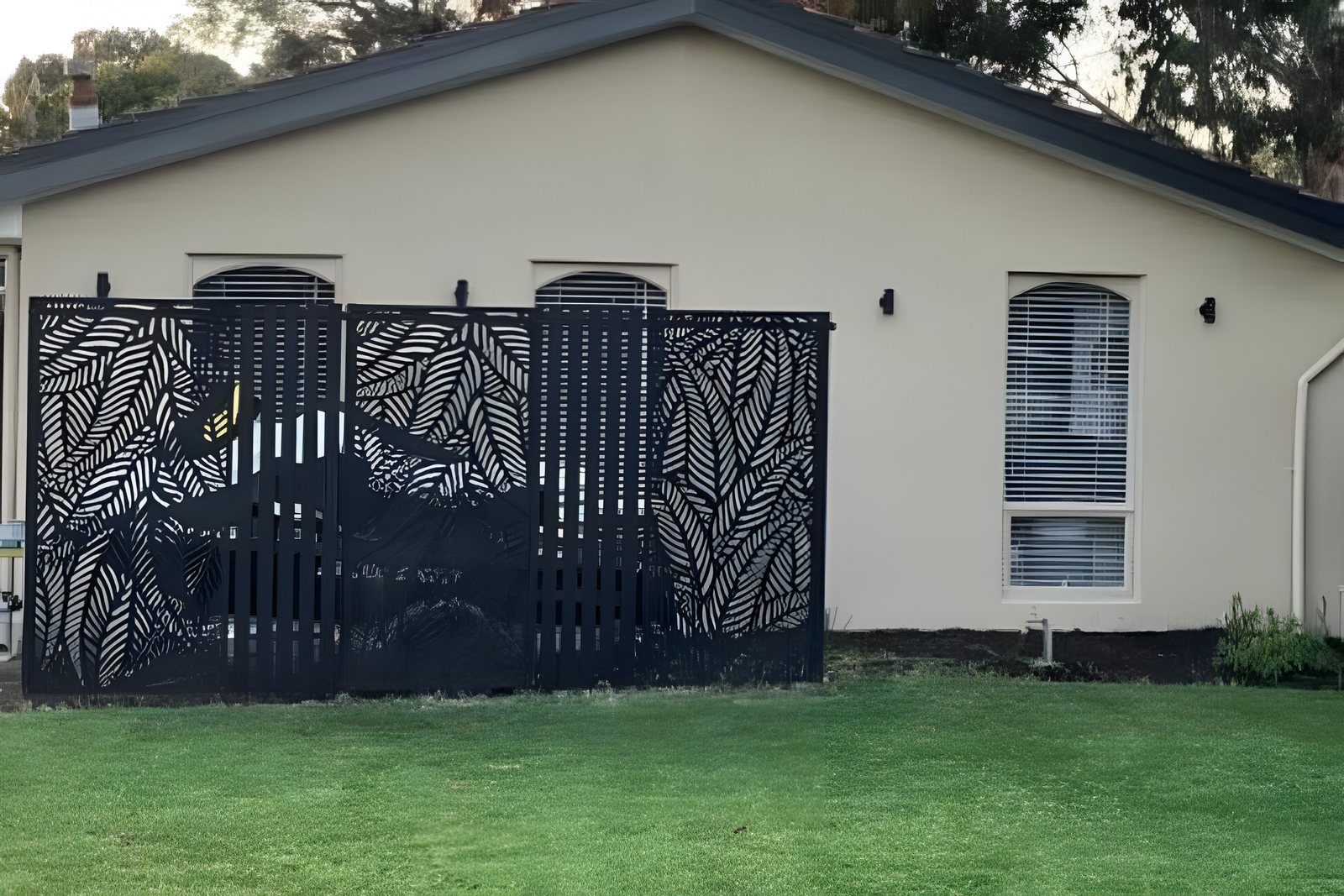 A finished lawn painting job, deep green turf in front of a house and a black screen fence